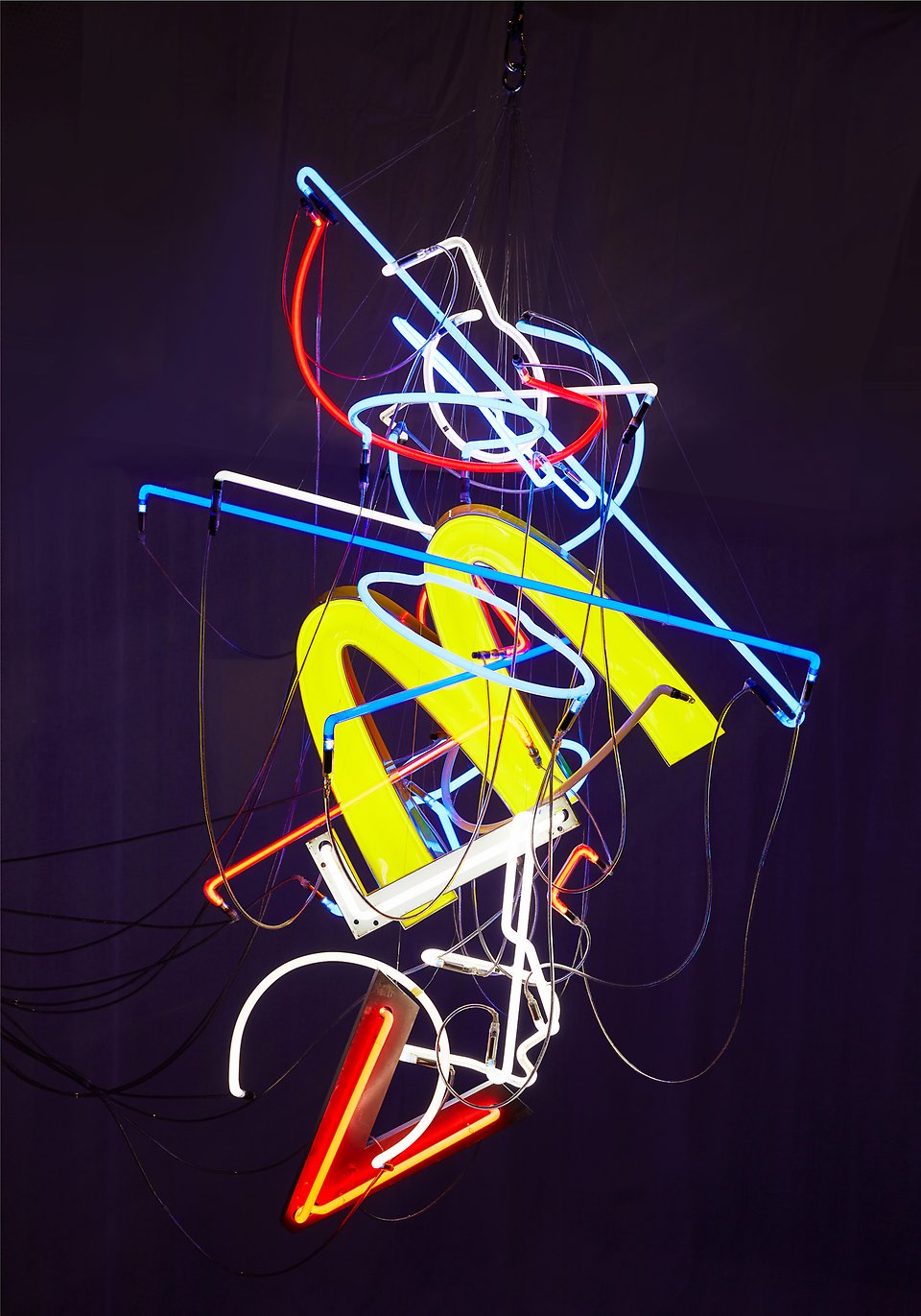 Olika neonskyltar har kopplats ihop och svävar mot mörk bakgrund. Konstverk skapat av Sara Sjöbäck. 