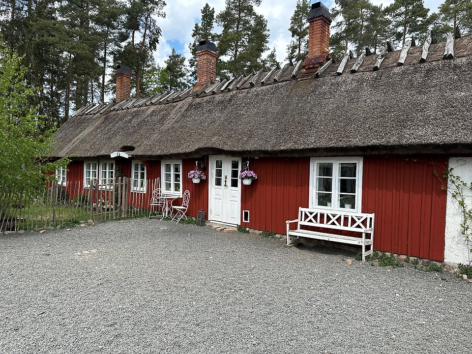 Lenas hus med nymålad röd panel och halmtak